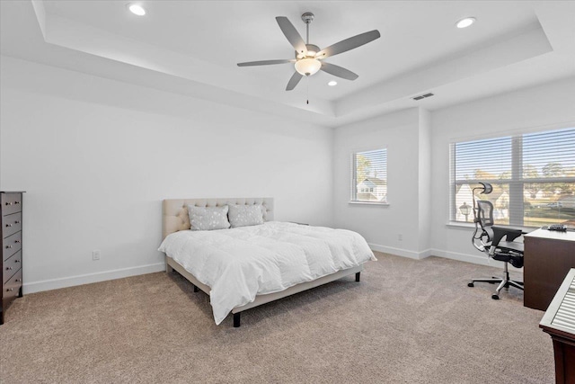 carpeted bedroom with a raised ceiling and ceiling fan