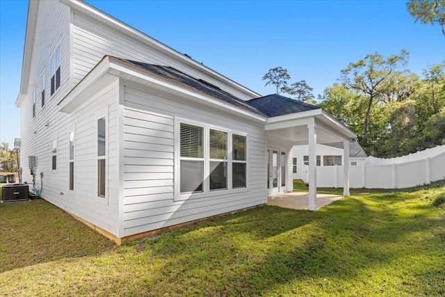 back of property with central AC unit, a patio area, and a lawn