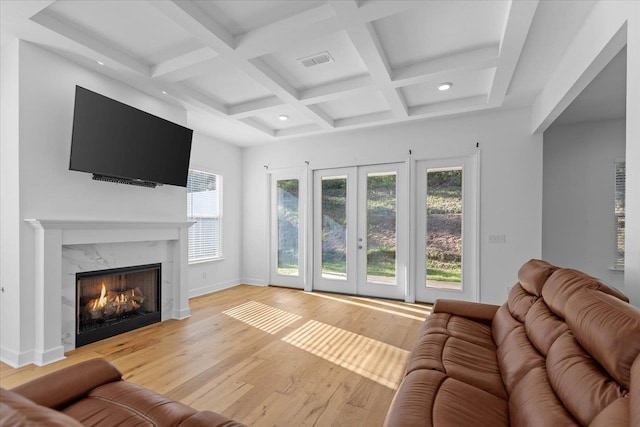 living room featuring coffered ceiling, light hardwood / wood-style flooring, a premium fireplace, and beamed ceiling