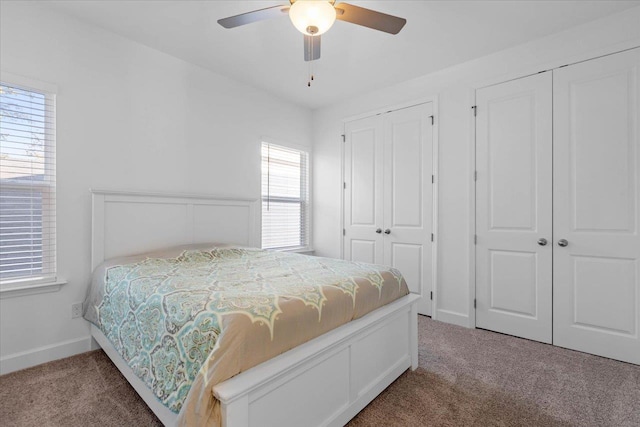 bedroom with ceiling fan, multiple closets, and carpet flooring