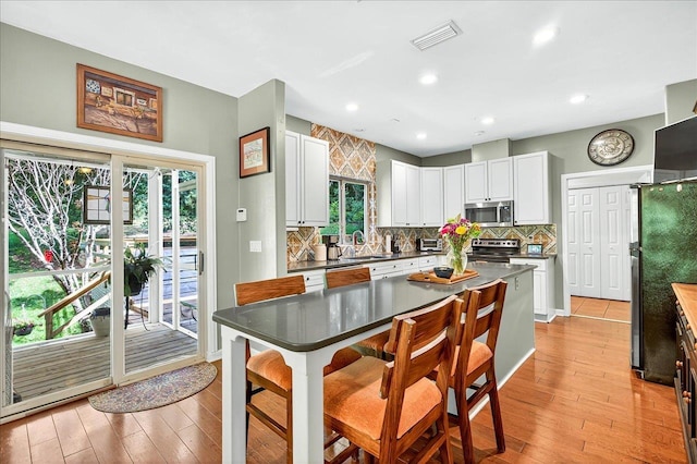 3508 Trillium Ct, Tallahassee, FL 32312 - kitchen featuring appliances with stainless steel finishes, tasteful backsplash, white cabinets, light wood finished floors, and dark countertops