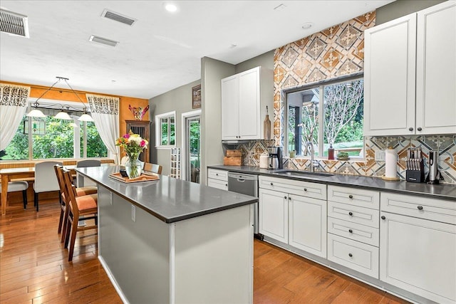 3508 Trillium Ct, Tallahassee, FL 32312 - kitchen featuring stainless steel dishwasher, dark countertops, decorative backsplash, white cabinetry, and a center island