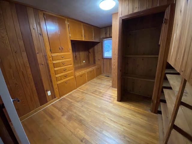 hallway featuring light wood-type flooring and wood walls