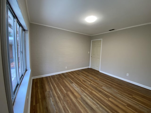 unfurnished room featuring ornamental molding, a wealth of natural light, and dark hardwood / wood-style flooring