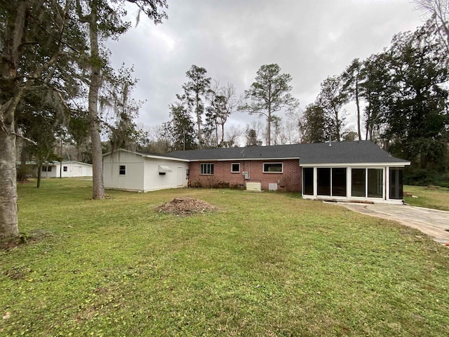 rear view of house featuring a yard and a sunroom