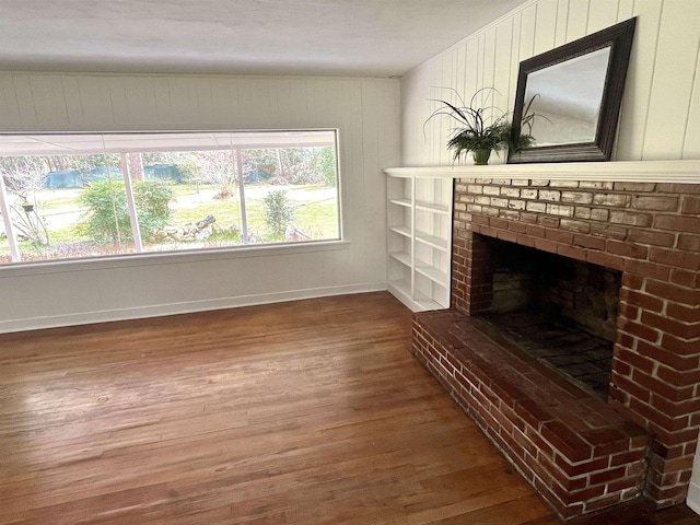 unfurnished living room featuring hardwood / wood-style flooring, a fireplace, and wood walls