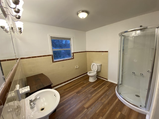 bathroom featuring wood-type flooring, a shower with door, and tile walls