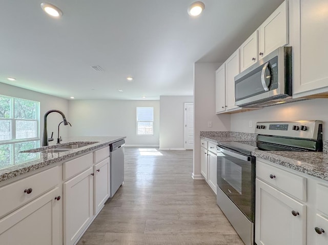 kitchen with sink, light hardwood / wood-style flooring, appliances with stainless steel finishes, light stone countertops, and white cabinets