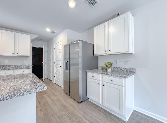 kitchen with white cabinetry, light hardwood / wood-style floors, stainless steel fridge with ice dispenser, and light stone counters