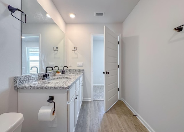 bathroom with wood-type flooring, vanity, and toilet