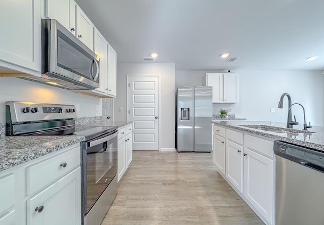 kitchen featuring white cabinetry, appliances with stainless steel finishes, sink, and light stone counters