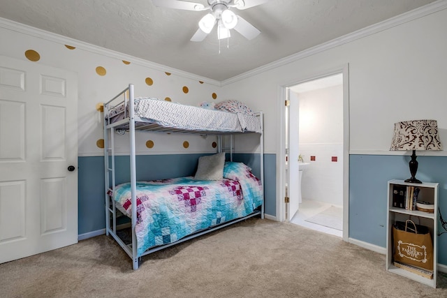 carpeted bedroom featuring ensuite bathroom, ceiling fan, and ornamental molding