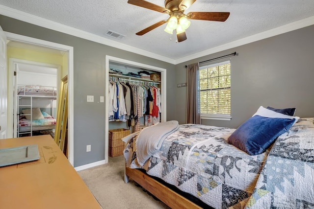 bedroom with ceiling fan, ornamental molding, a textured ceiling, light colored carpet, and a closet