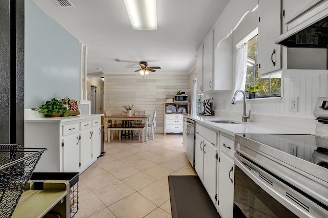 kitchen with stove, sink, light tile patterned floors, white cabinetry, and range hood