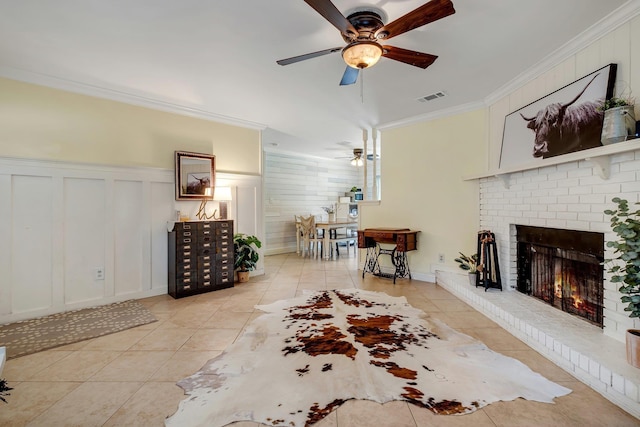 living room featuring light tile patterned floors, a brick fireplace, ceiling fan, and crown molding