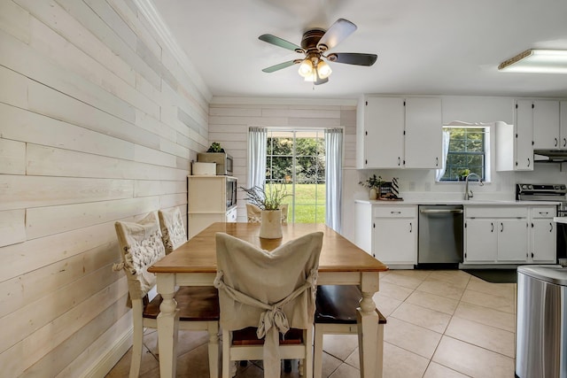 tiled dining area featuring sink, ceiling fan, and wood walls