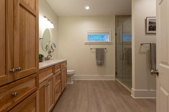 bathroom featuring toilet, vanity, wood-type flooring, and a shower with door