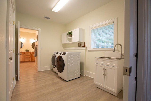 laundry area with cabinets, light hardwood / wood-style floors, washing machine and dryer, and sink