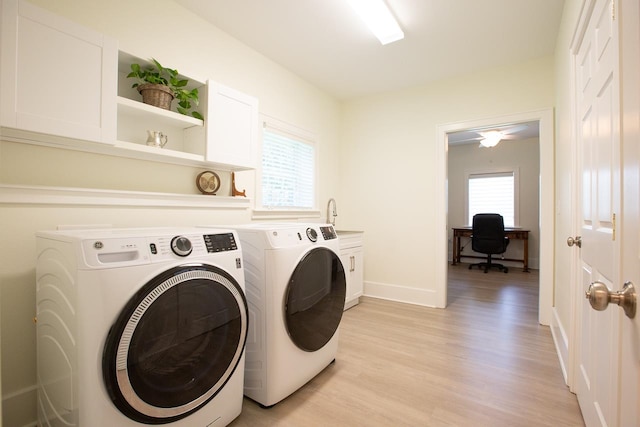 laundry room with cabinets, light hardwood / wood-style floors, plenty of natural light, and washing machine and dryer