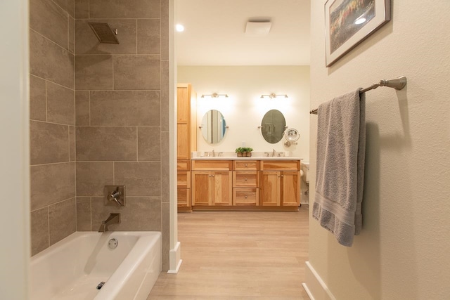 bathroom featuring hardwood / wood-style floors, vanity, and tiled shower / bath combo