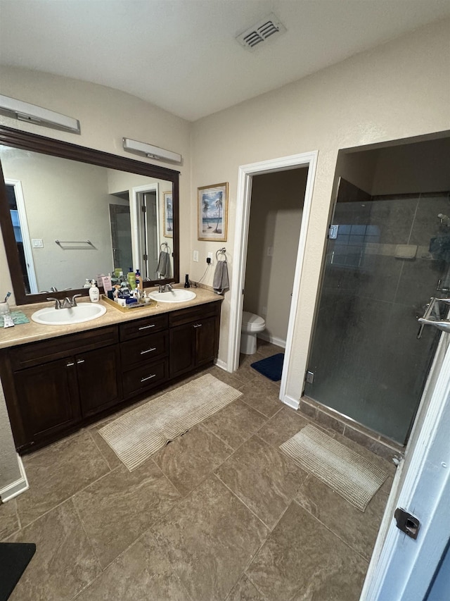 bathroom with toilet, vanity, and a shower with door