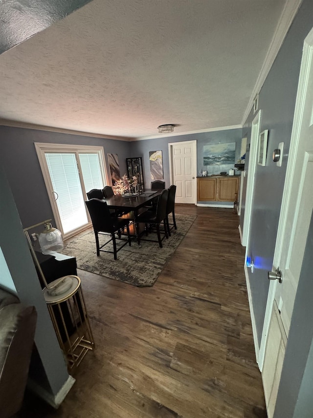 dining area with a textured ceiling, dark wood-type flooring, and ornamental molding