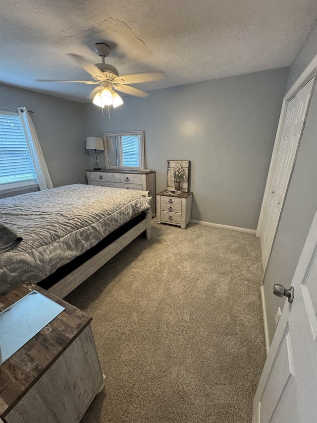 carpeted bedroom with ceiling fan and a textured ceiling