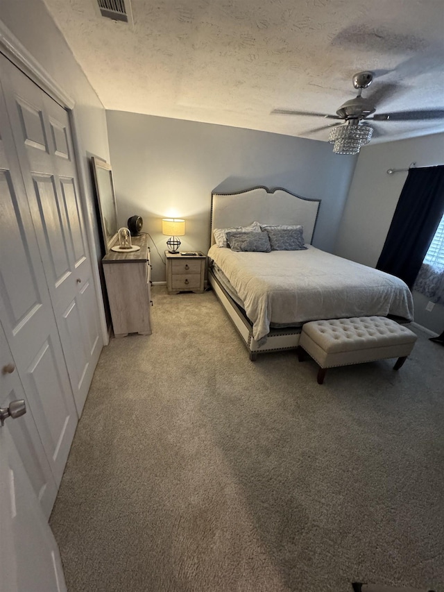 carpeted bedroom with ceiling fan and a textured ceiling