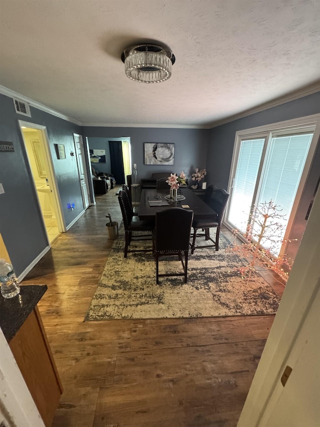 dining room featuring dark hardwood / wood-style flooring, a textured ceiling, and ornamental molding