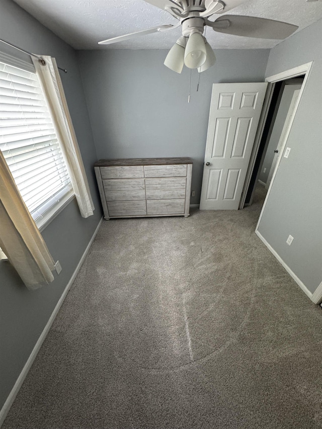 unfurnished bedroom with a textured ceiling, carpet, and ceiling fan