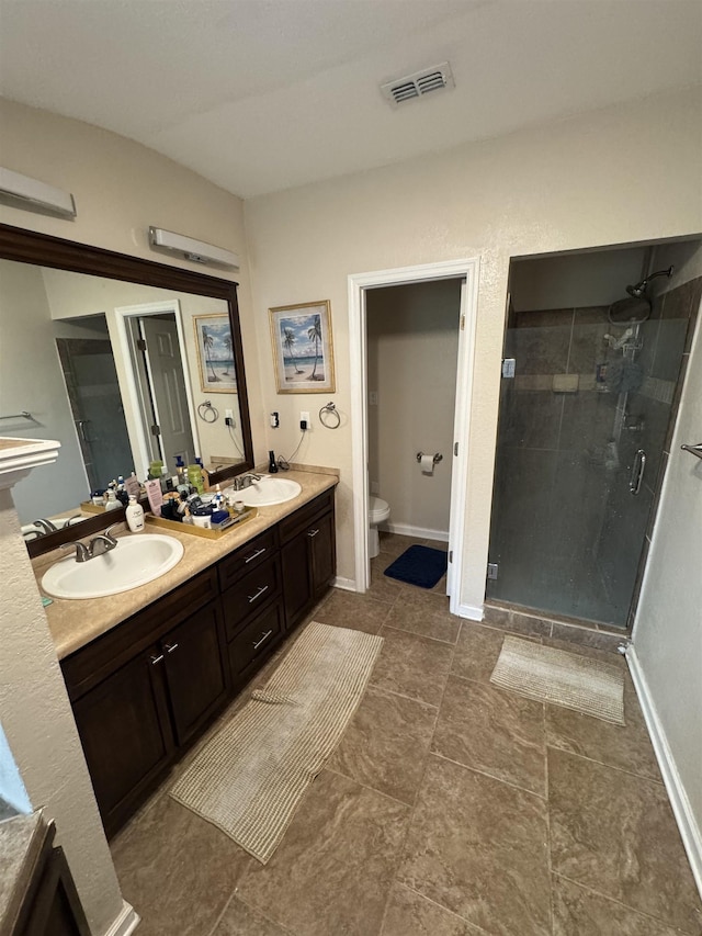 bathroom featuring toilet, vanity, and a shower with shower door