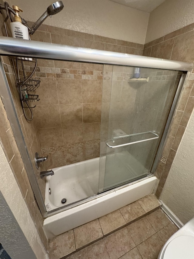 bathroom featuring tile patterned floors and bath / shower combo with glass door