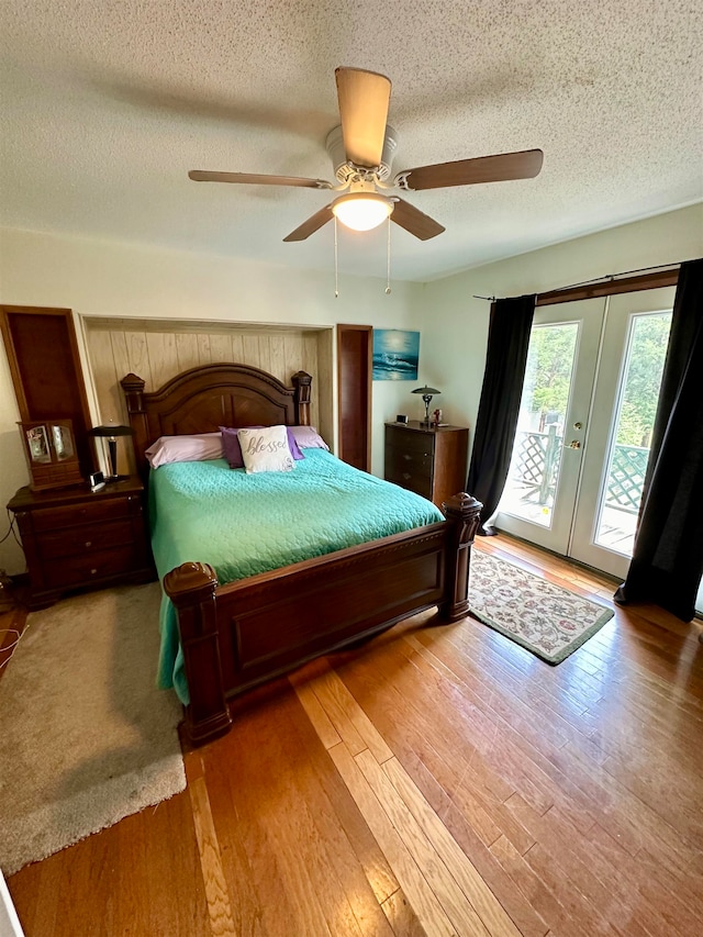 bedroom featuring access to outside, french doors, hardwood / wood-style floors, a textured ceiling, and ceiling fan