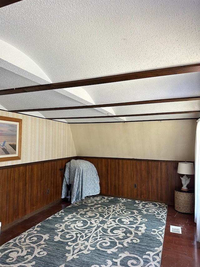 bedroom with dark hardwood / wood-style flooring, wooden walls, and a textured ceiling