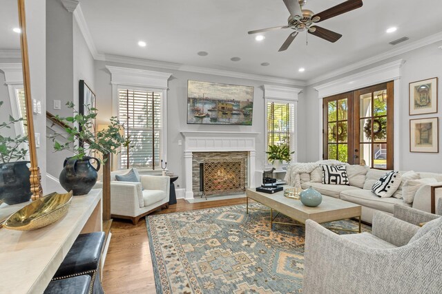 1216 Mitchell Ave, Tallahassee, FL 32303 - living room featuring a fireplace with flush hearth, visible vents, ornamental molding, light wood-type flooring, and ceiling fan