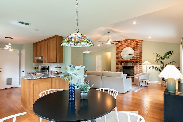 696 Lupine Ln, Tallahassee, FL 32308 - dining room with a ceiling fan, light wood finished floors, vaulted ceiling, and a fireplace