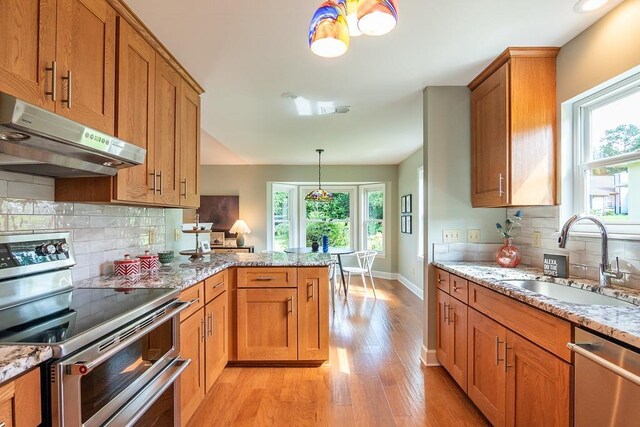 696 Lupine Ln, Tallahassee, FL 32308 - kitchen featuring appliances with stainless steel finishes, under cabinet range hood, light wood-style flooring, brown cabinets, and a peninsula