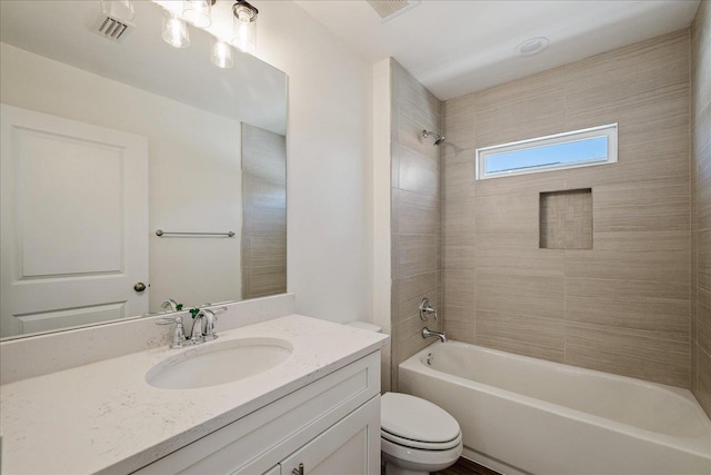 full bathroom with tiled shower / bath, vanity, and toilet