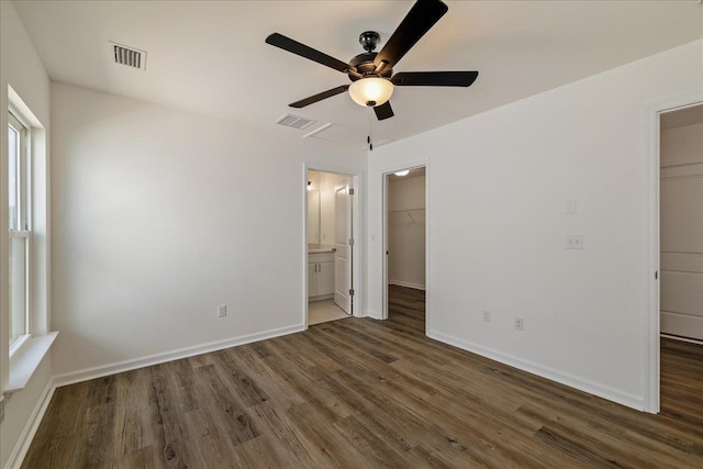 unfurnished bedroom featuring ceiling fan, dark hardwood / wood-style floors, ensuite bathroom, a spacious closet, and a closet