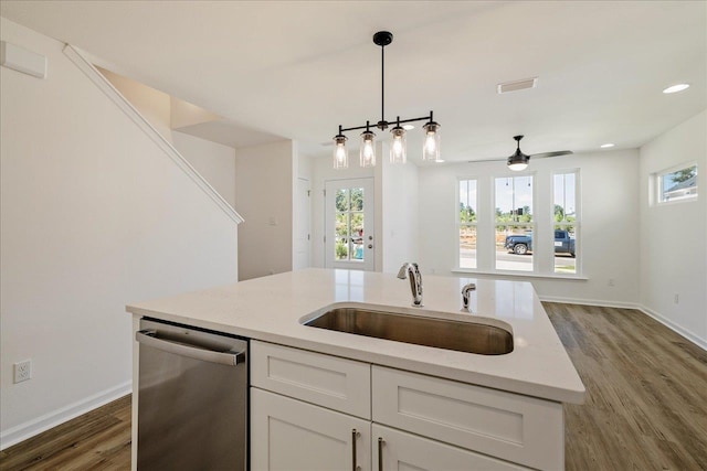 kitchen with light stone counters, stainless steel dishwasher, sink, and white cabinets