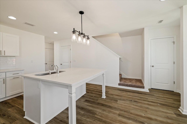 kitchen featuring pendant lighting, white cabinetry, tasteful backsplash, and an island with sink