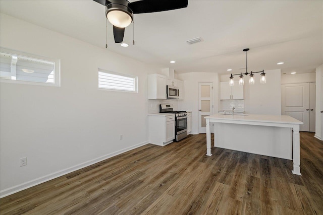 kitchen with tasteful backsplash, sink, white cabinets, stainless steel appliances, and a center island with sink