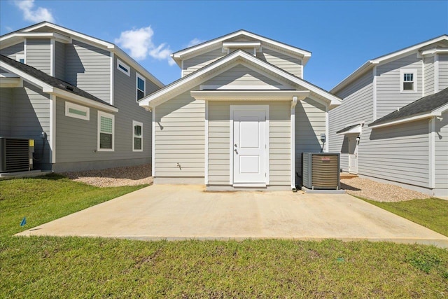 rear view of house featuring cooling unit, a patio, and a lawn