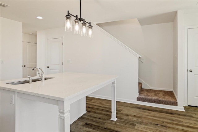 kitchen with a center island with sink, sink, pendant lighting, and dark wood-type flooring