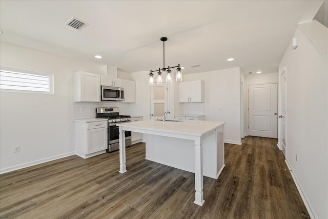 kitchen featuring pendant lighting, white cabinetry, appliances with stainless steel finishes, and a center island with sink