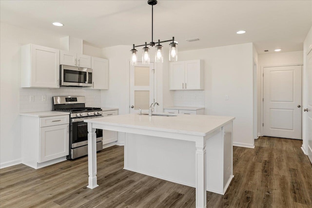 kitchen featuring sink, white cabinetry, decorative light fixtures, stainless steel appliances, and a kitchen island with sink