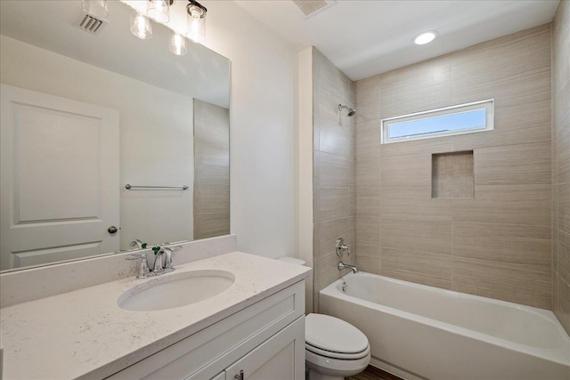 full bathroom with tiled shower / bath, vanity, and toilet