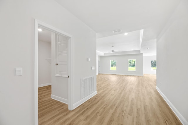 hall featuring a tray ceiling and light hardwood / wood-style floors