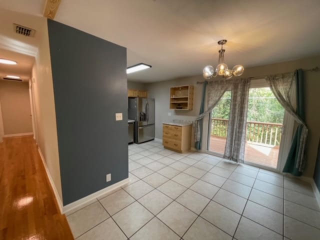 kitchen featuring an inviting chandelier, light tile patterned flooring, and stainless steel fridge