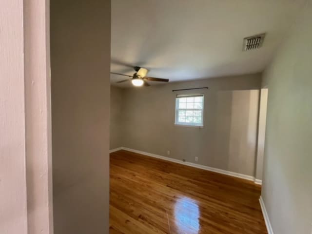 empty room with hardwood / wood-style floors and ceiling fan